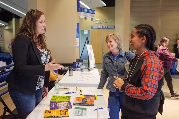 a UNCA representative speaking with a prospective student at a college fair