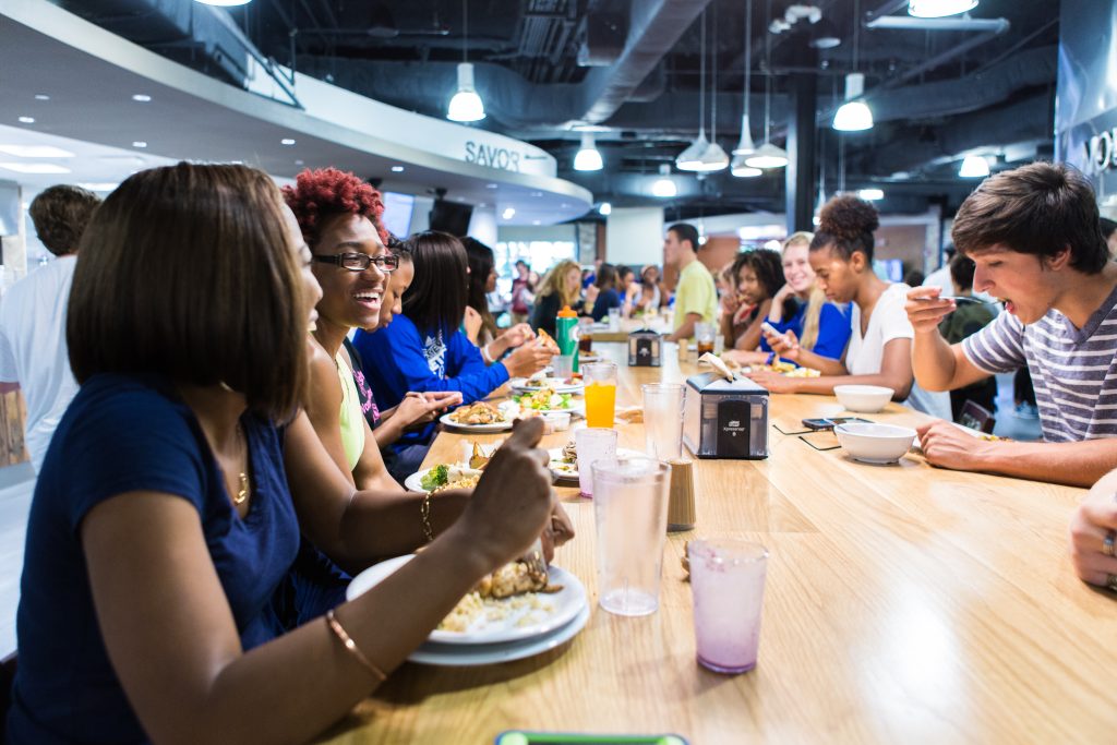 Students smiling, laughing at a dining table in Brown Hall