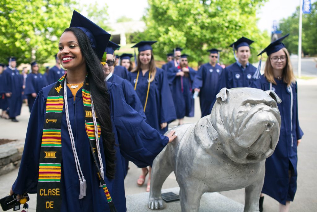 Graduates in their gowns touching the Rocky statue at Commencement 2018