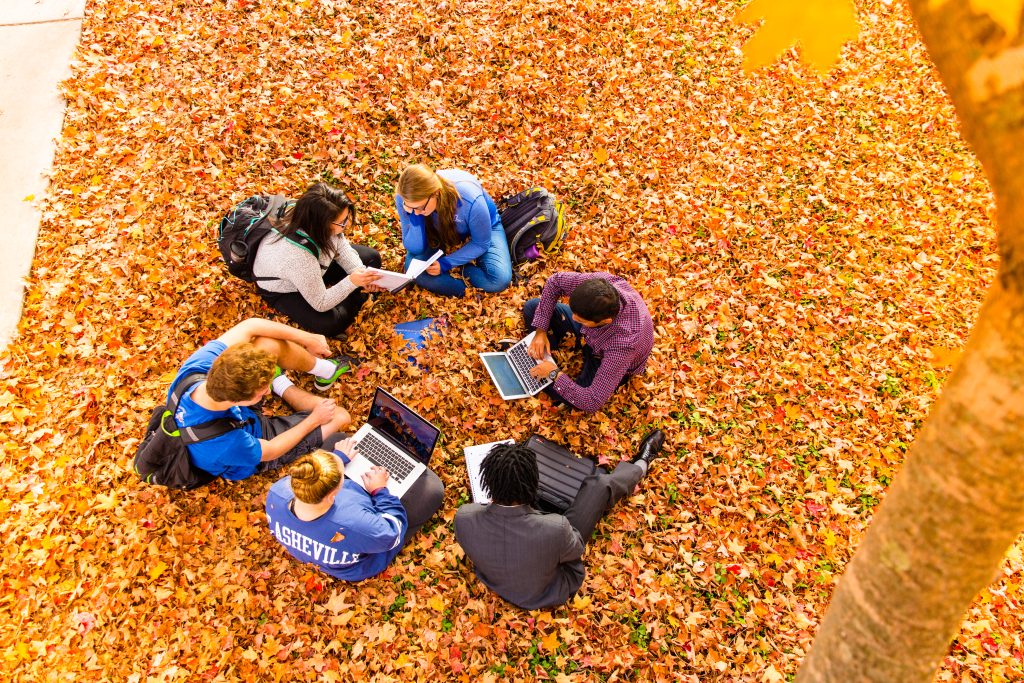 Students sitting in a circle on fall leaves