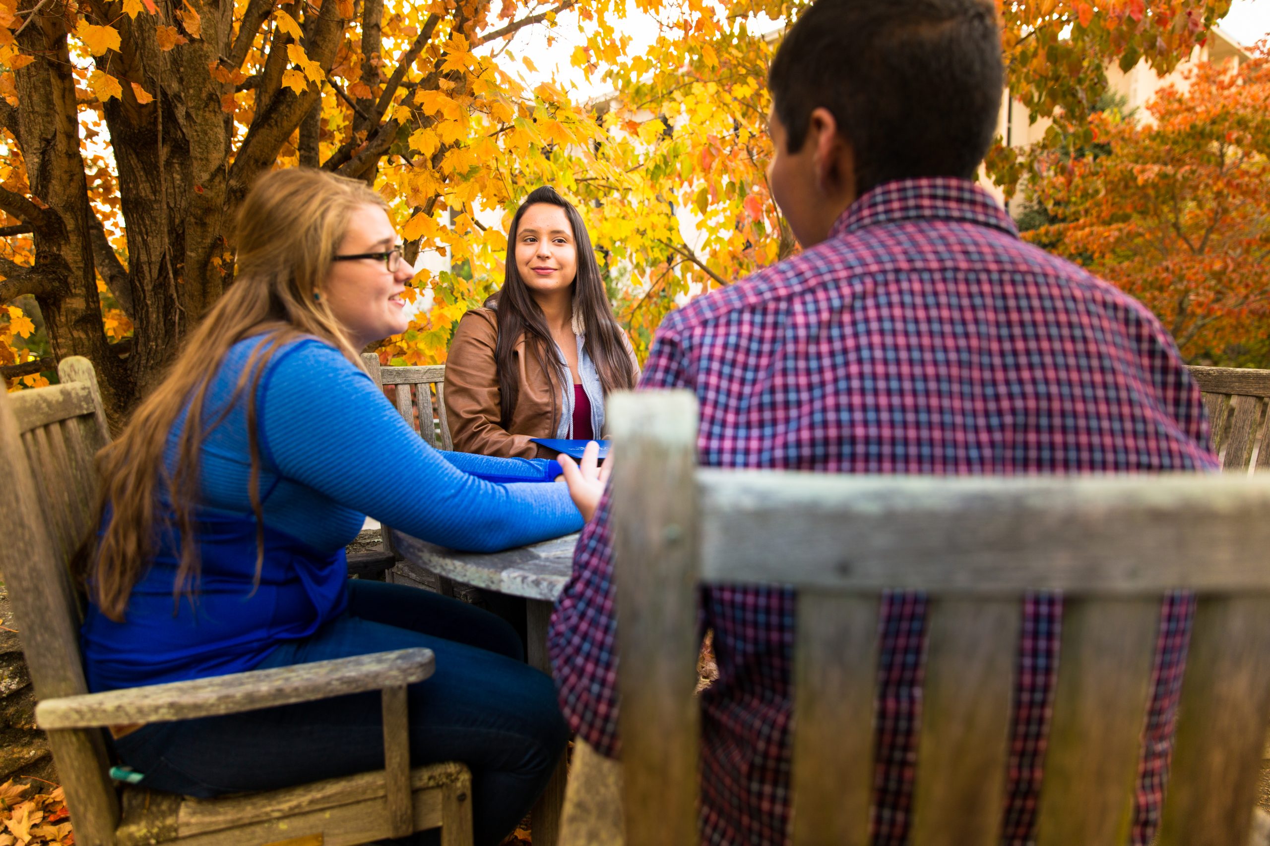 Students sitting around a table on the quad in the fall