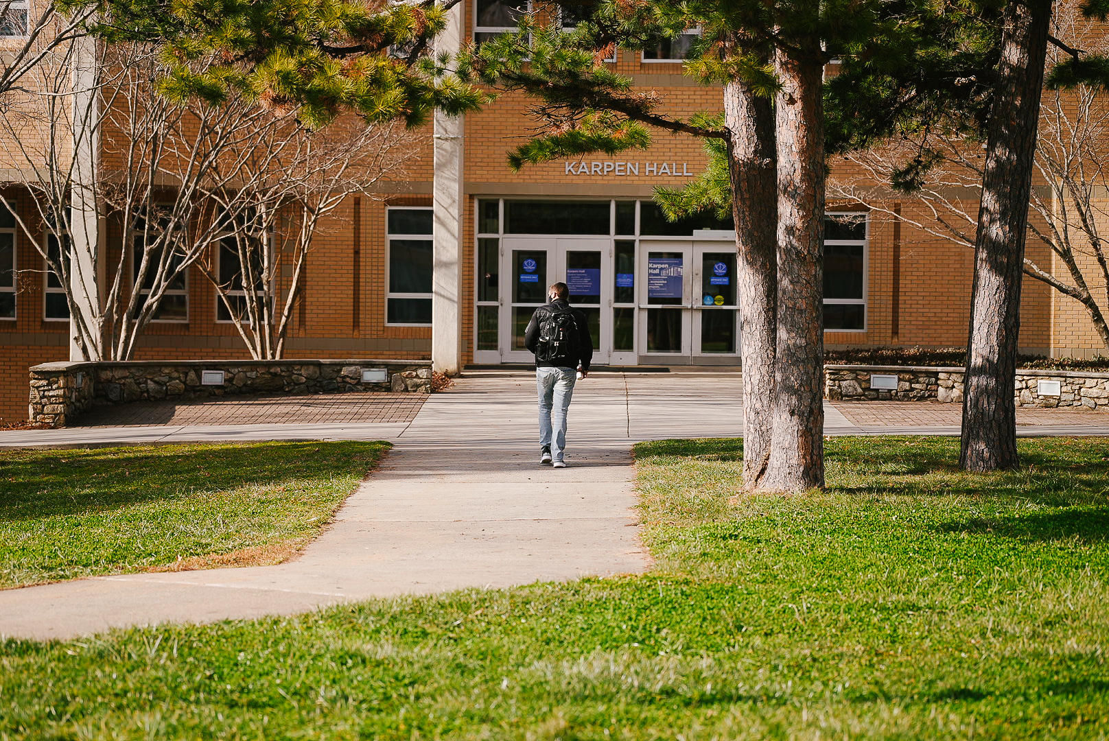 A person walking toward the front doors of Karpen hall
