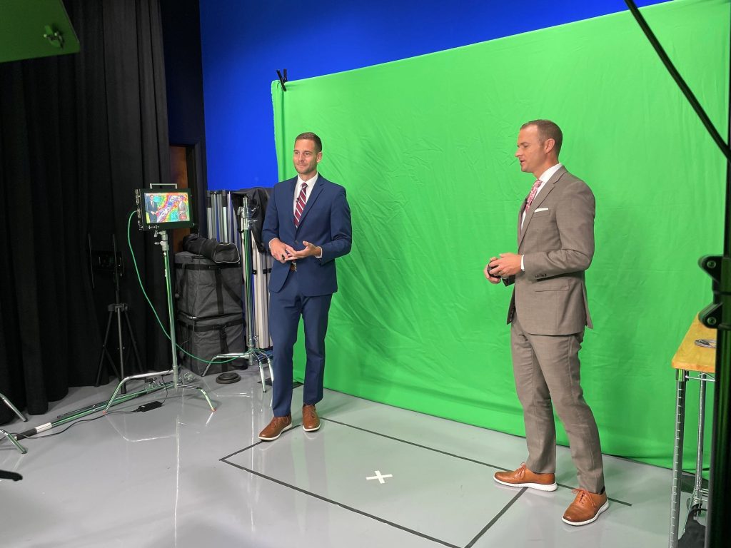 Two people in front of a green screen in a studio